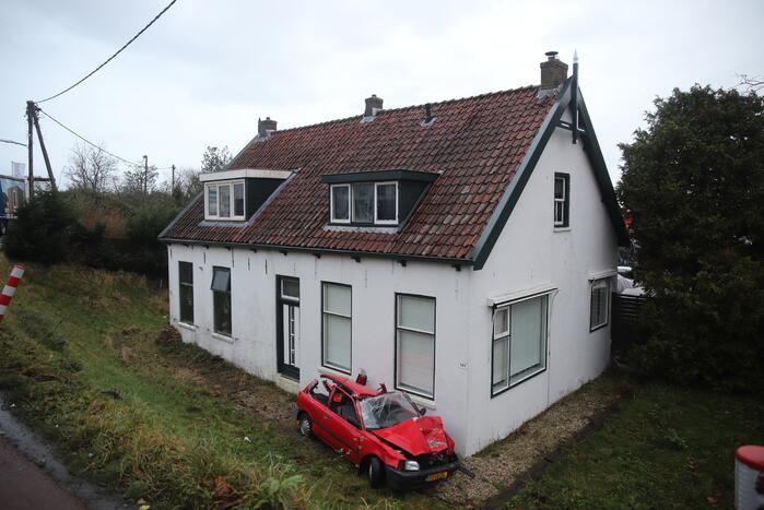 Auto rijdt van dijk en knalt tegen woning