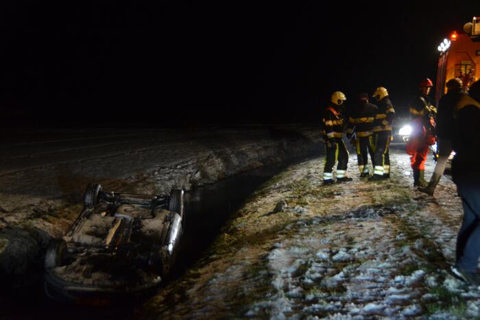 Auto glijdt van de weg en belandt op de kop in sloot