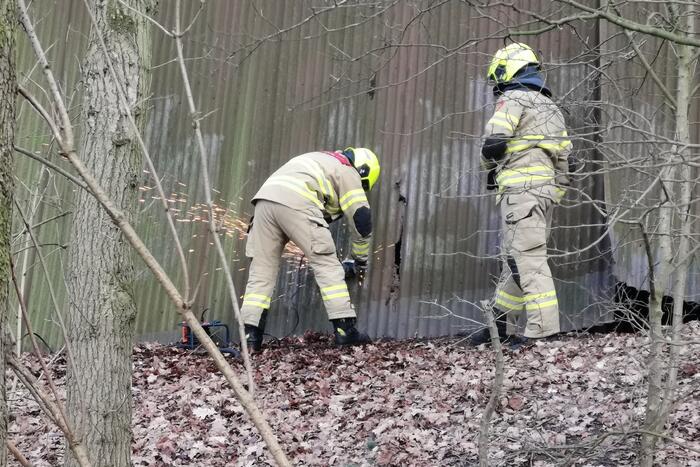Brandweer blust brand in muur van golfplaten
