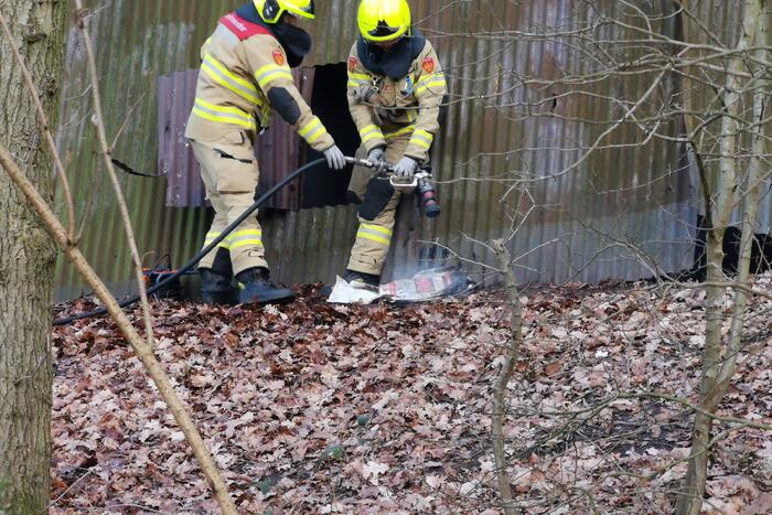 Brandweer blust brand in muur van golfplaten