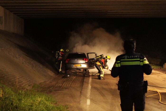 Auto vat vlam onder viaduct snelweg