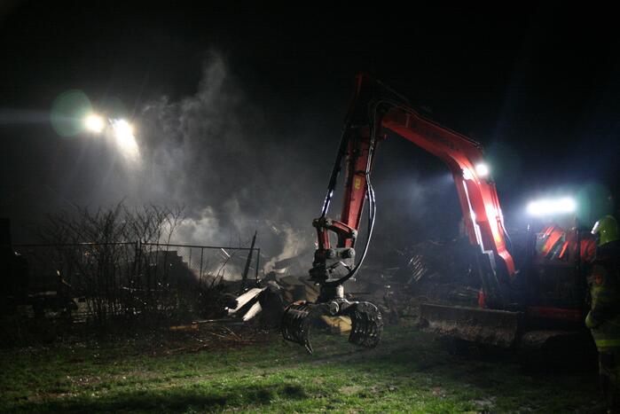 Grote uitslaande brand in loods achter woning