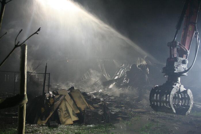 Grote uitslaande brand in loods achter woning