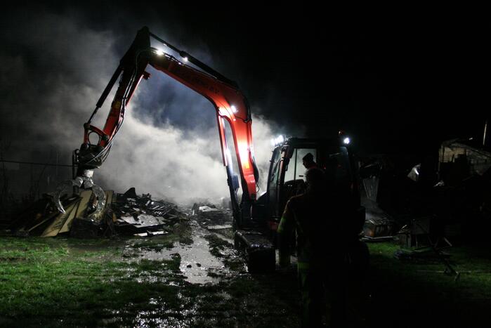 Grote uitslaande brand in loods achter woning