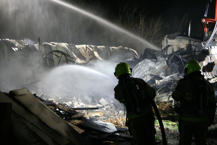 Grote uitslaande brand in loods achter woning