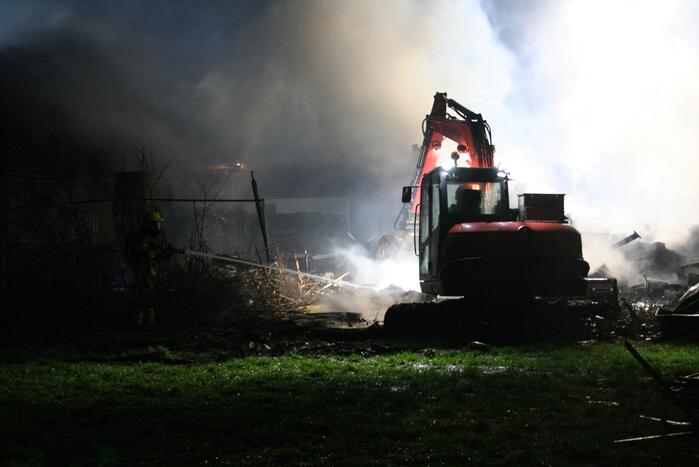 Grote uitslaande brand in loods achter woning