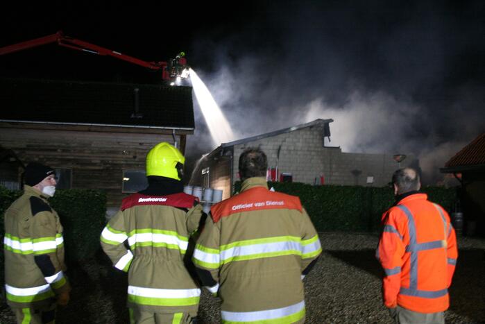 Grote uitslaande brand in loods achter woning