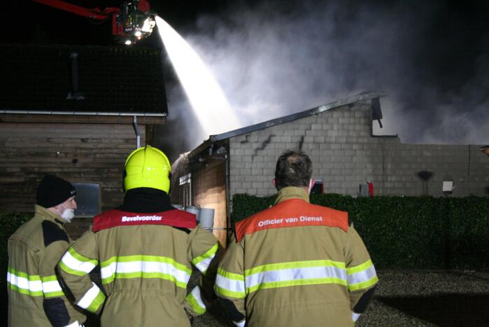 Grote uitslaande brand in loods achter woning