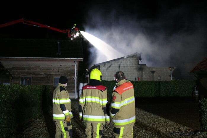Grote uitslaande brand in loods achter woning