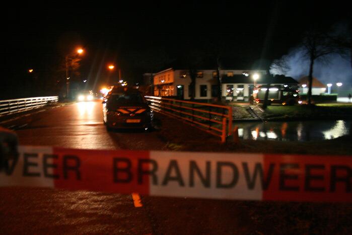 Grote uitslaande brand in loods achter woning
