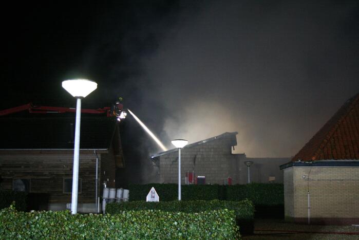 Grote uitslaande brand in loods achter woning