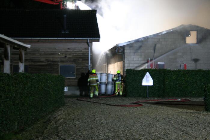 Grote uitslaande brand in loods achter woning