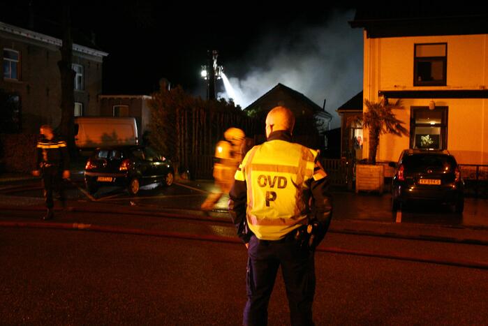 Grote uitslaande brand in loods achter woning