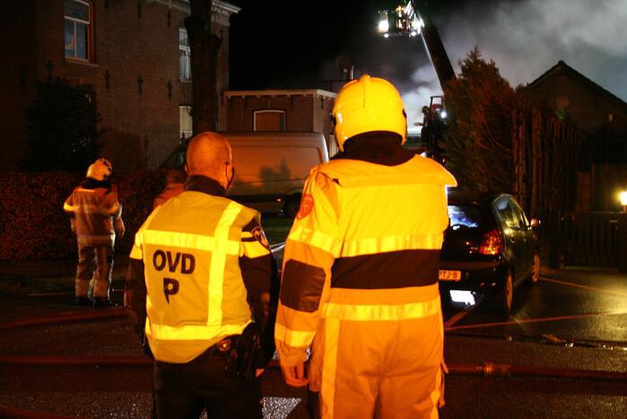 Grote uitslaande brand in loods achter woning