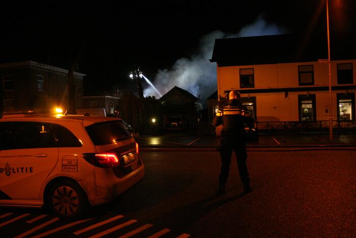 Grote uitslaande brand in loods achter woning