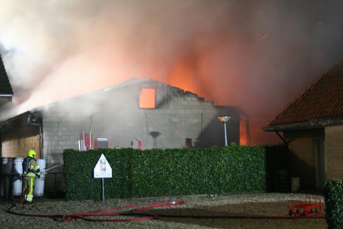 Grote uitslaande brand in loods achter woning