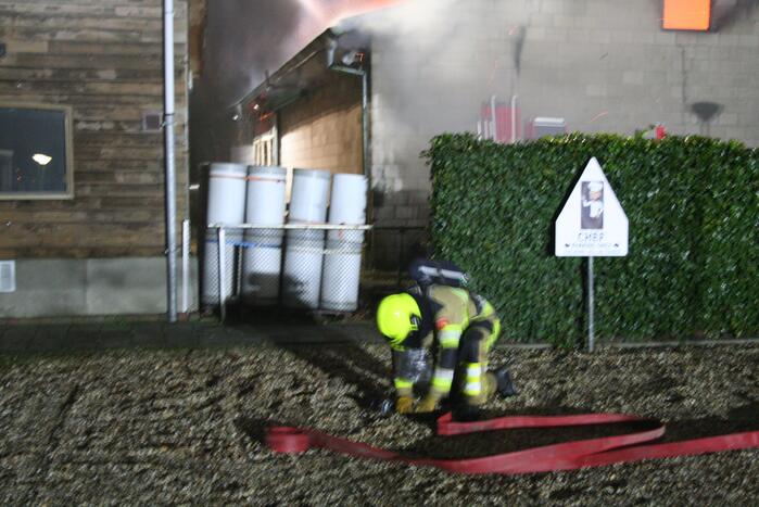 Grote uitslaande brand in loods achter woning