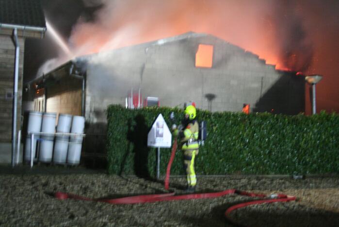 Grote uitslaande brand in loods achter woning