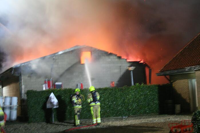 Grote uitslaande brand in loods achter woning