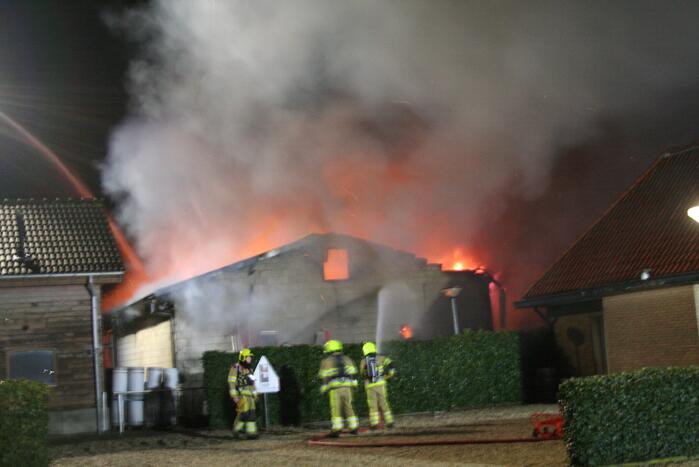 Grote uitslaande brand in loods achter woning