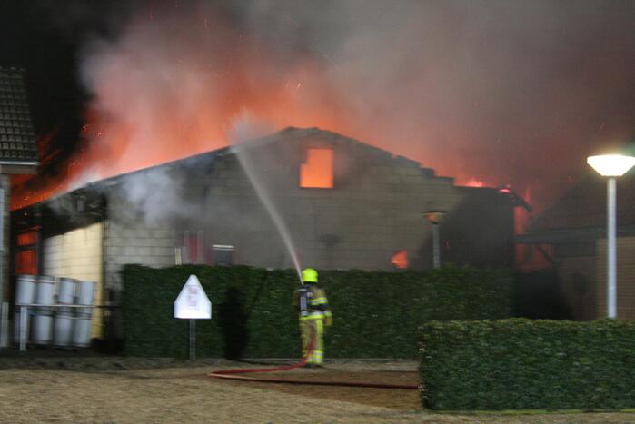 Grote uitslaande brand in loods achter woning