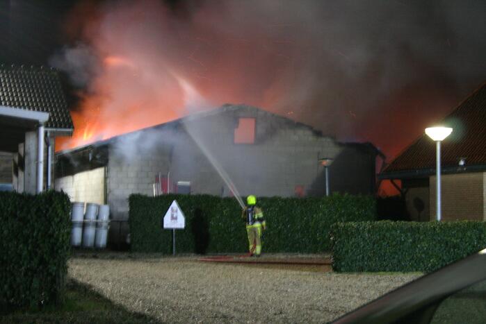 Grote uitslaande brand in loods achter woning
