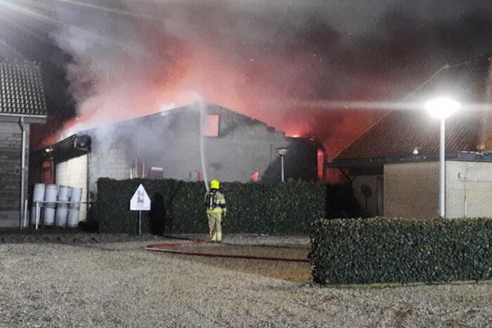 Grote uitslaande brand in loods achter woning
