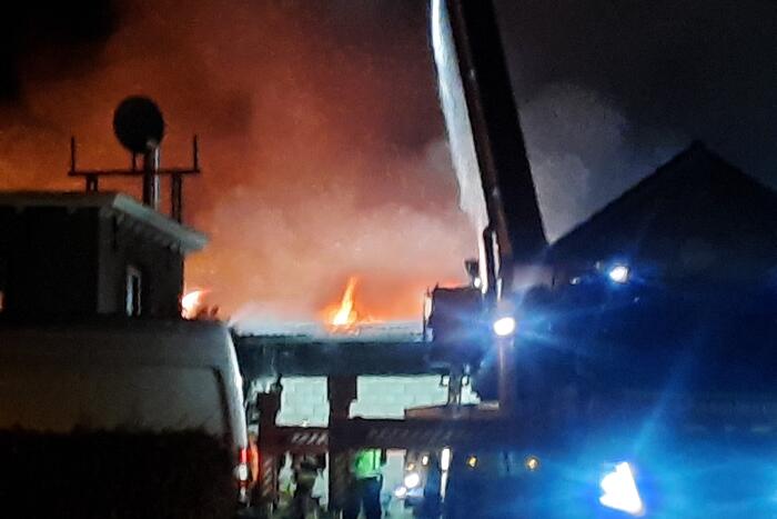 Grote uitslaande brand in loods achter woning