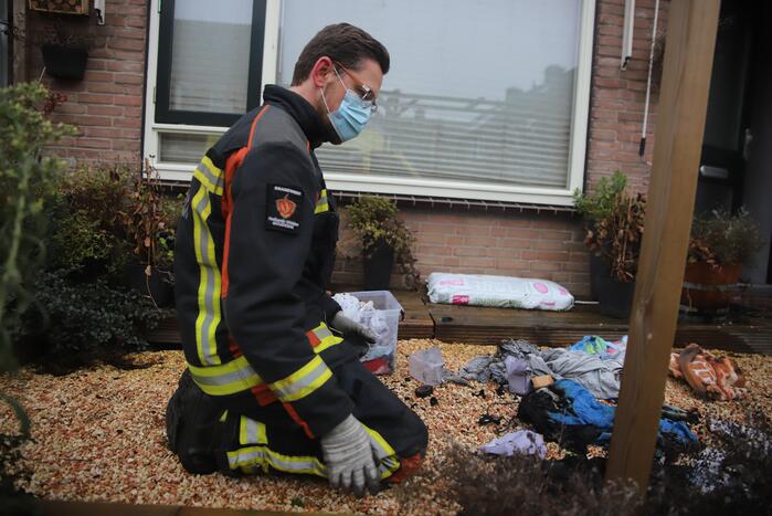 Kleding in woning vliegt in brand