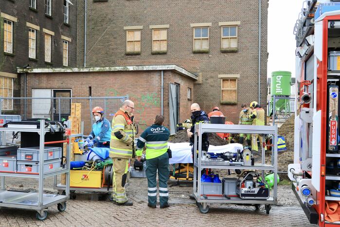 Persoon bekneld onder betonnen plaat