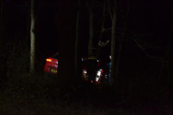 Auto vliegt uit de bocht en belandt tussen de bomen
