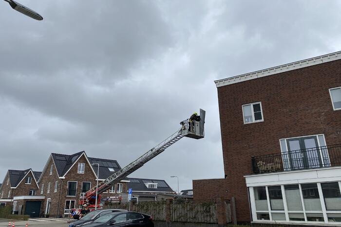 Brandweer haalt losgewaaide platen van dak