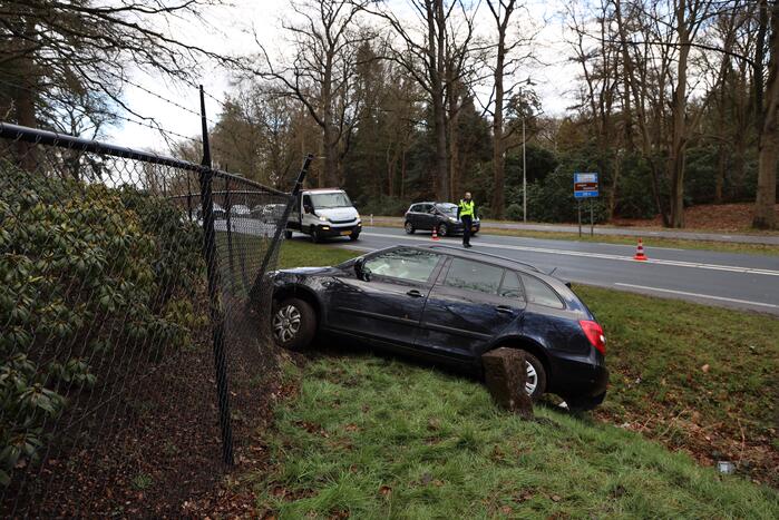 Auto eindigt aan overkant van de weg in hekwerk