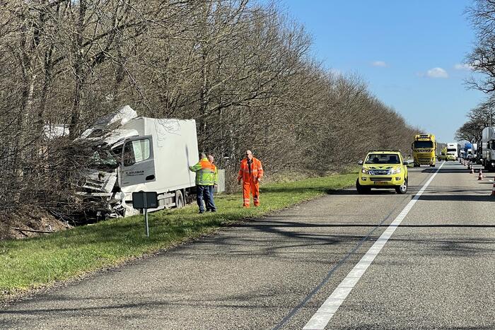 Vrachtwagen belandt in berm tegen boom