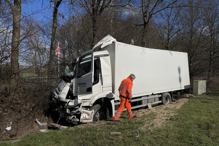 Vrachtwagen belandt in berm tegen boom