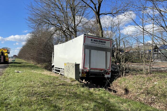 Vrachtwagen belandt in berm tegen boom