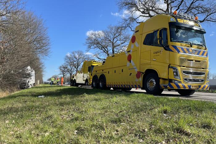 Vrachtwagen belandt in berm tegen boom