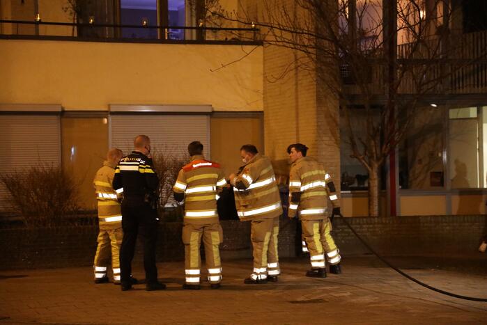 Brandweer blust brandende papiercontainer