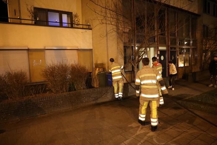 Brandweer blust brandende papiercontainer