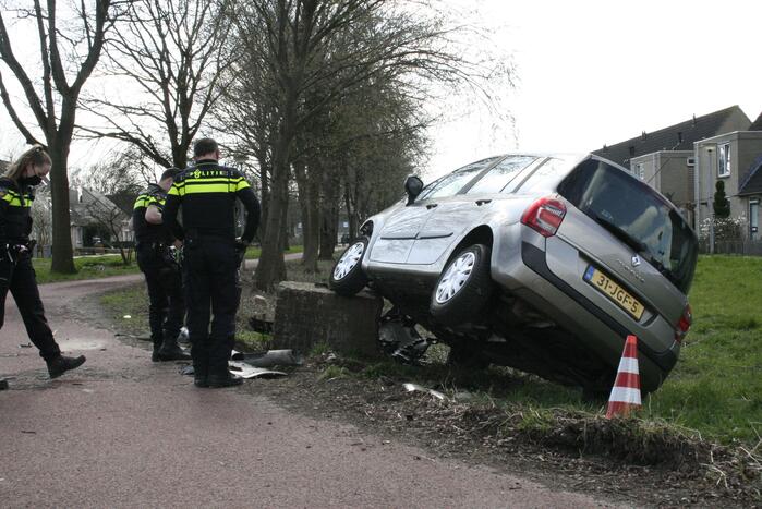Auto botst op betonblok met lantaarnpaal
