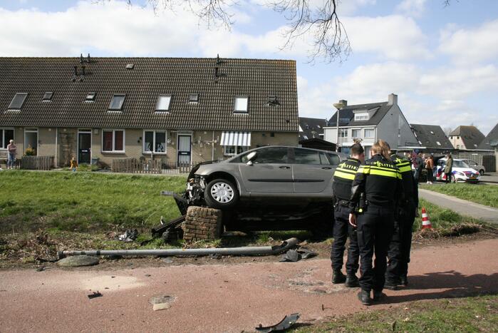 Auto botst op betonblok met lantaarnpaal