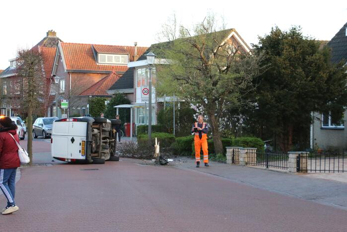Busje op zijn kant na botsing met boom