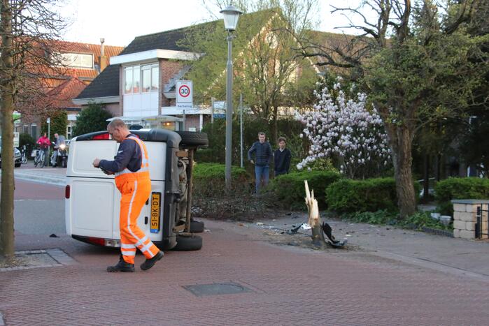 Busje op zijn kant na botsing met boom