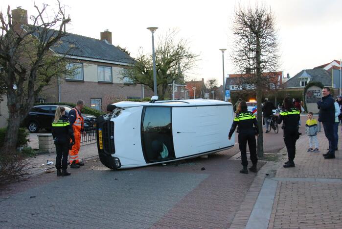 Busje op zijn kant na botsing met boom