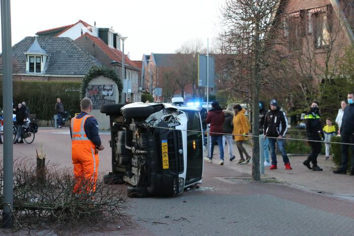 Busje op zijn kant na botsing met boom