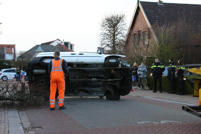 Busje op zijn kant na botsing met boom