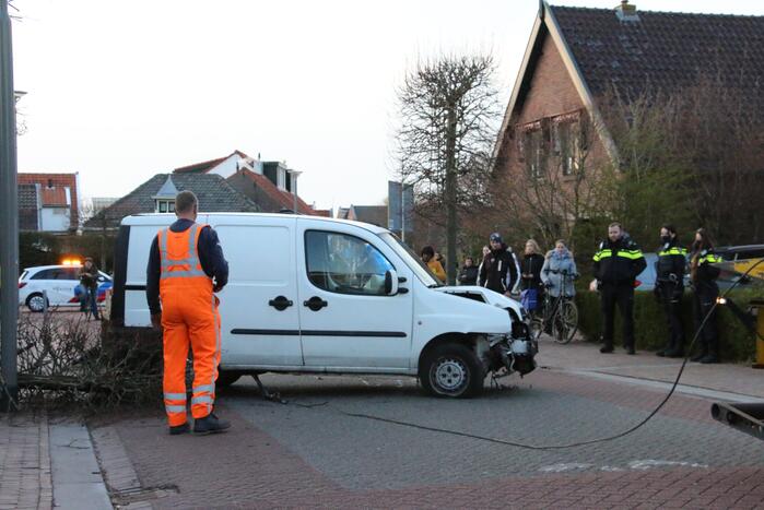 Busje op zijn kant na botsing met boom
