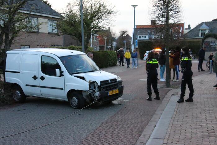 Busje op zijn kant na botsing met boom