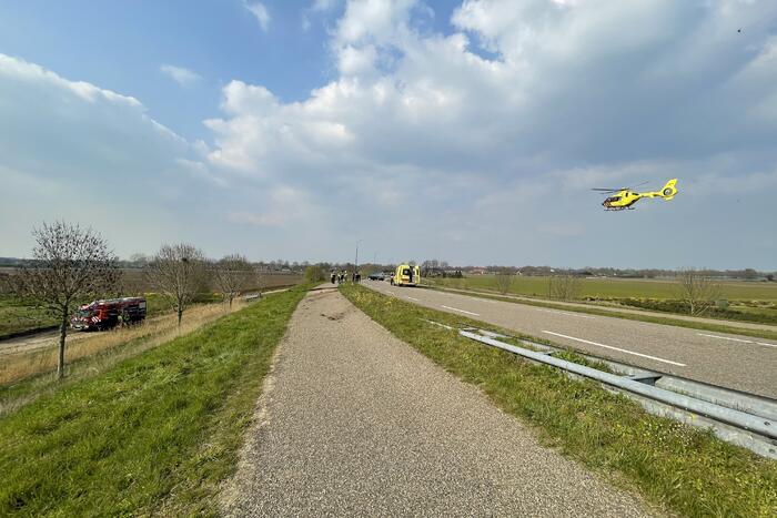 Auto glijdt van dijk af na botsing en vliegt in brand