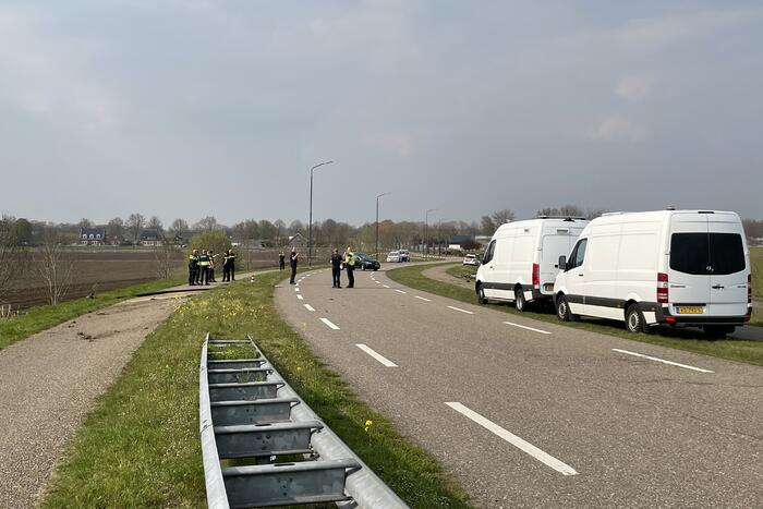 Auto glijdt van dijk af na botsing en vliegt in brand